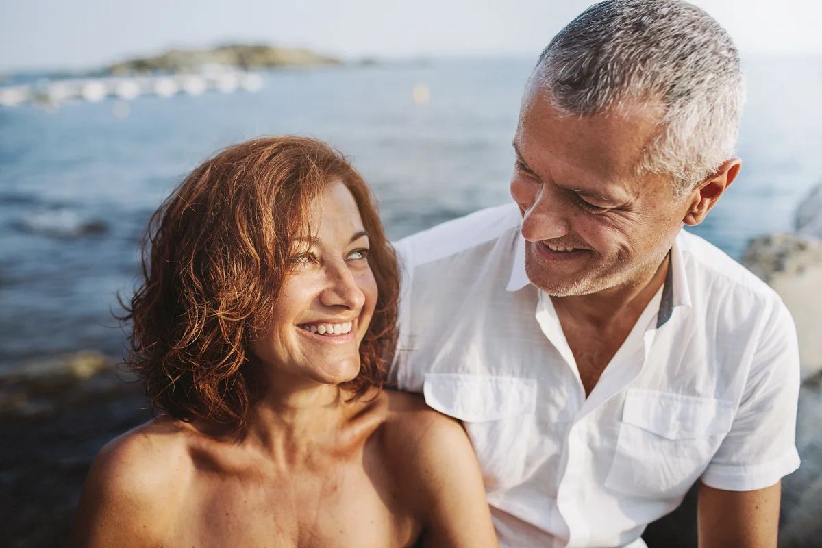 Pareja en la playa mirándose y sonriendo