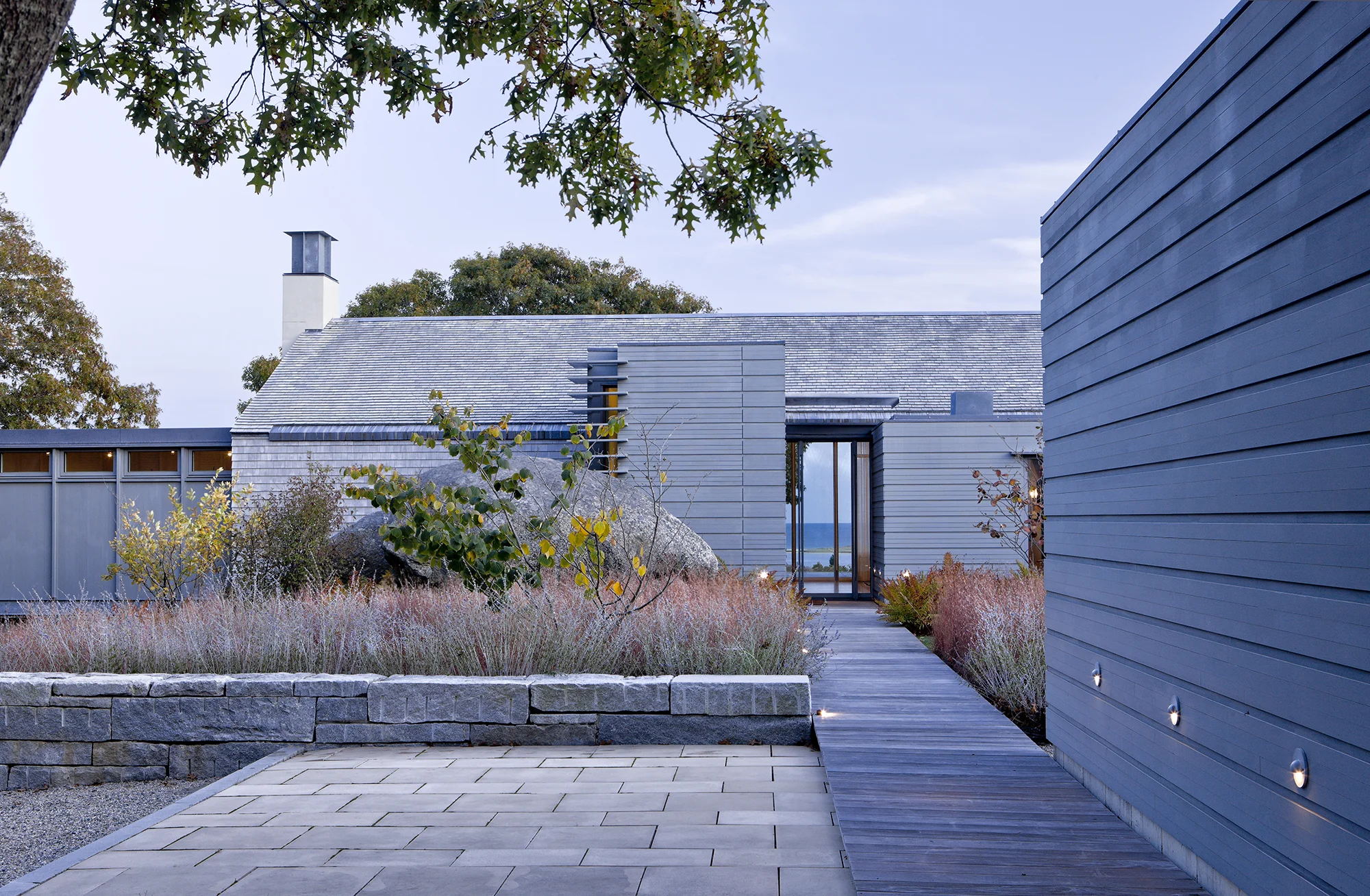 Set high on the terminal moraine of Martha’s Vineyard, this 4-acre project emphasizes the unique quality a glacial landscape providing sweeping ocean views to the South. Existing glacial erratics and mature trees are woven into a design, which employs a minimal number of walls and terraces to ground the house to the site. Close collaboration between the architect and landscape architect fostered a strong continuity of spatial organization and materiality between interior and exterior spaces, effectively blurring the boundaries between inside and outside. A strong interplay exists between the native landscape and the “man made” program of the design, which weave seamlessly through the spaces created by large existing trees and boulders. The pool, constructed into the hillside, provides the unique juxtaposition of water's edge with distant ocean views. Recognition American Society of Landscape Architects | Honor Award 2016 Boston Society of Landscape Architects | Honor Award 2007 Collaborators Olson Sundberg Kundig Allen Architects Photography Charles Mayer Roger Foley