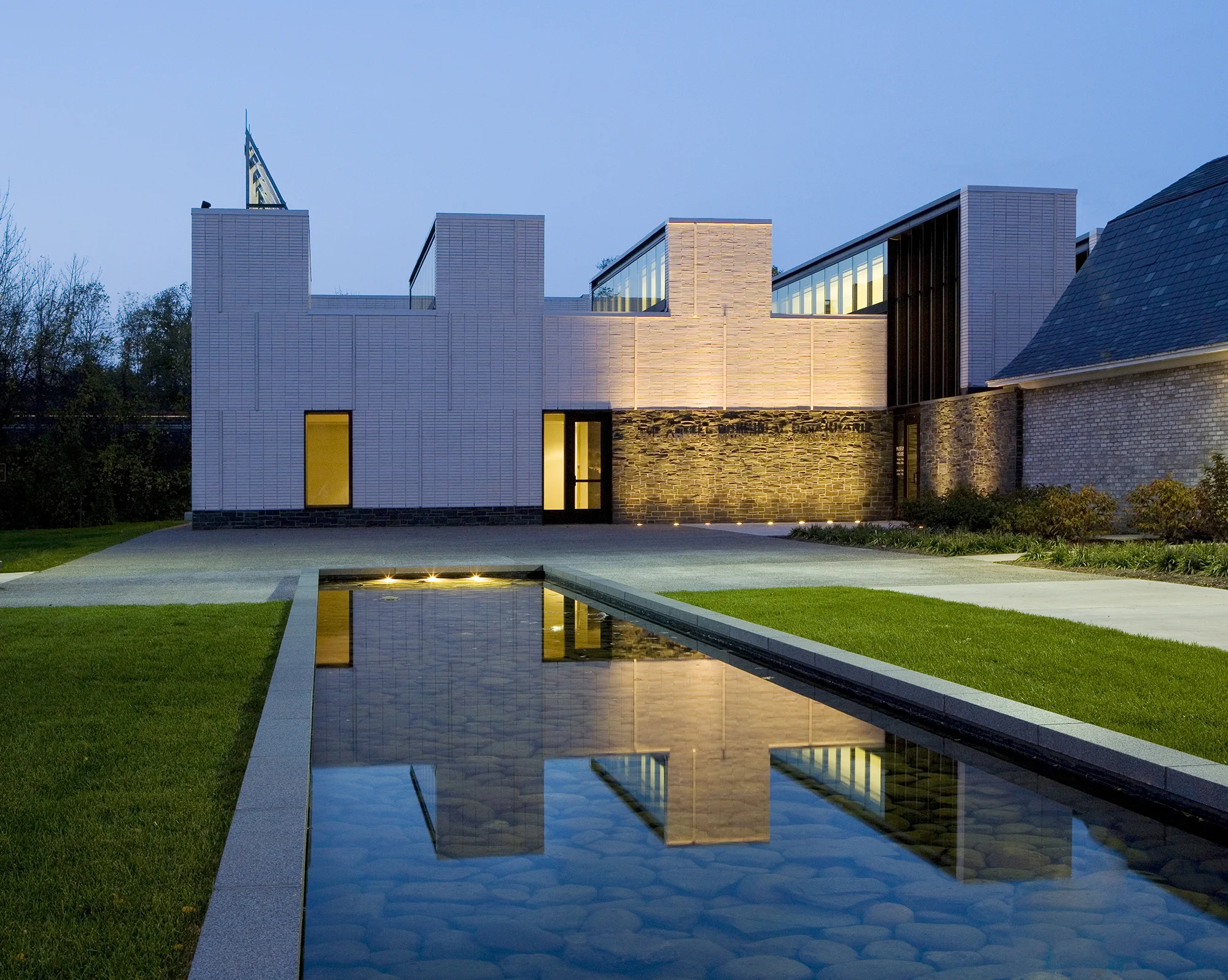 The Arkell Art Center is located on a seven-acre post-industrial site in the village of Canajoharie, on the banks of the Mohawk River. The museum weaves the site’s layers of manufacturing, art and patronage into a program of new and old elements. The project involved the renovation of a historic library, a modern gallery addition, and courtyards, an extensive parking area, field house, and open lawns for town gatherings. A long site canal was proposed as an organizing element and to recall the Erie Canal that once ran directly adjacent to the site on the southern edge. Abstracted landforms recalling geological eskers were used to frame views and create a separate landscape setting for art display and civic function. These elements, in coordination with the glowing boxes of the museum buildings extend the presence of the Art Center to the village and the adjacent New York State Thruway. Recognition Boston Society of Architects | Citation for Design 2008 Collaborators Ann Beha Architects designLAB Architects Photography Jonathan Hillyer