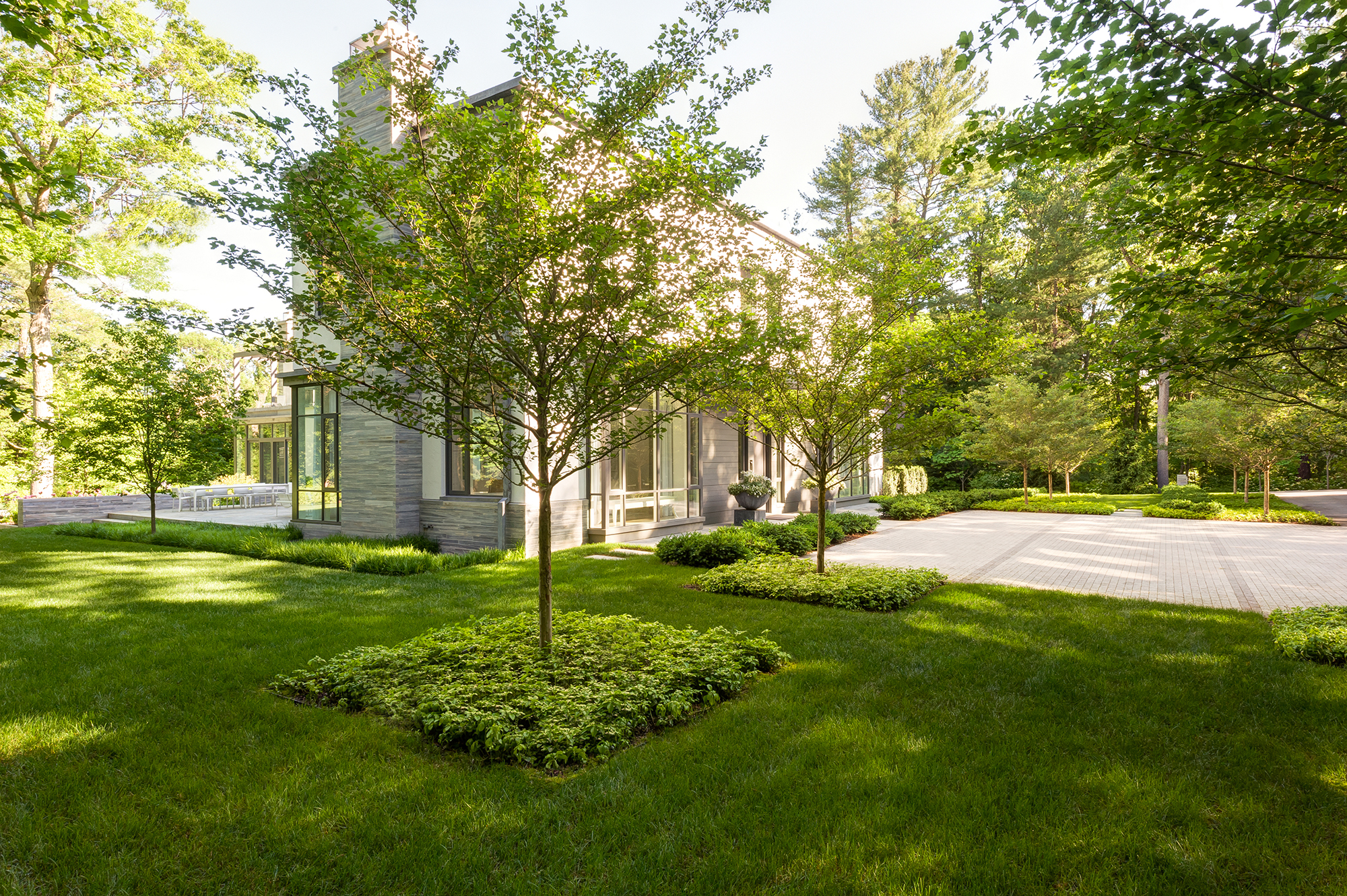 The site of this garden is adjacent to a large tract of conservation land that provided inspiration for the plant palette of this carefully crafted garden. The garden transitions from the curving forms of the north lawns, defined by the loose planting of flowering trees and an enriched woodland edge, to a series of formal intimate gardens and courts around the dwelling. The Weston Garden celebrates a simplicity language of the relationship between building and landscape. This minimalist design approach focuses on creating a harmonious connection to the indoor and outdoor spaces for the residents. Collaborators Stern McCafferty Architect The Jillson Company, Inc. Photography Rosemary Fletcher Ngoc Doan