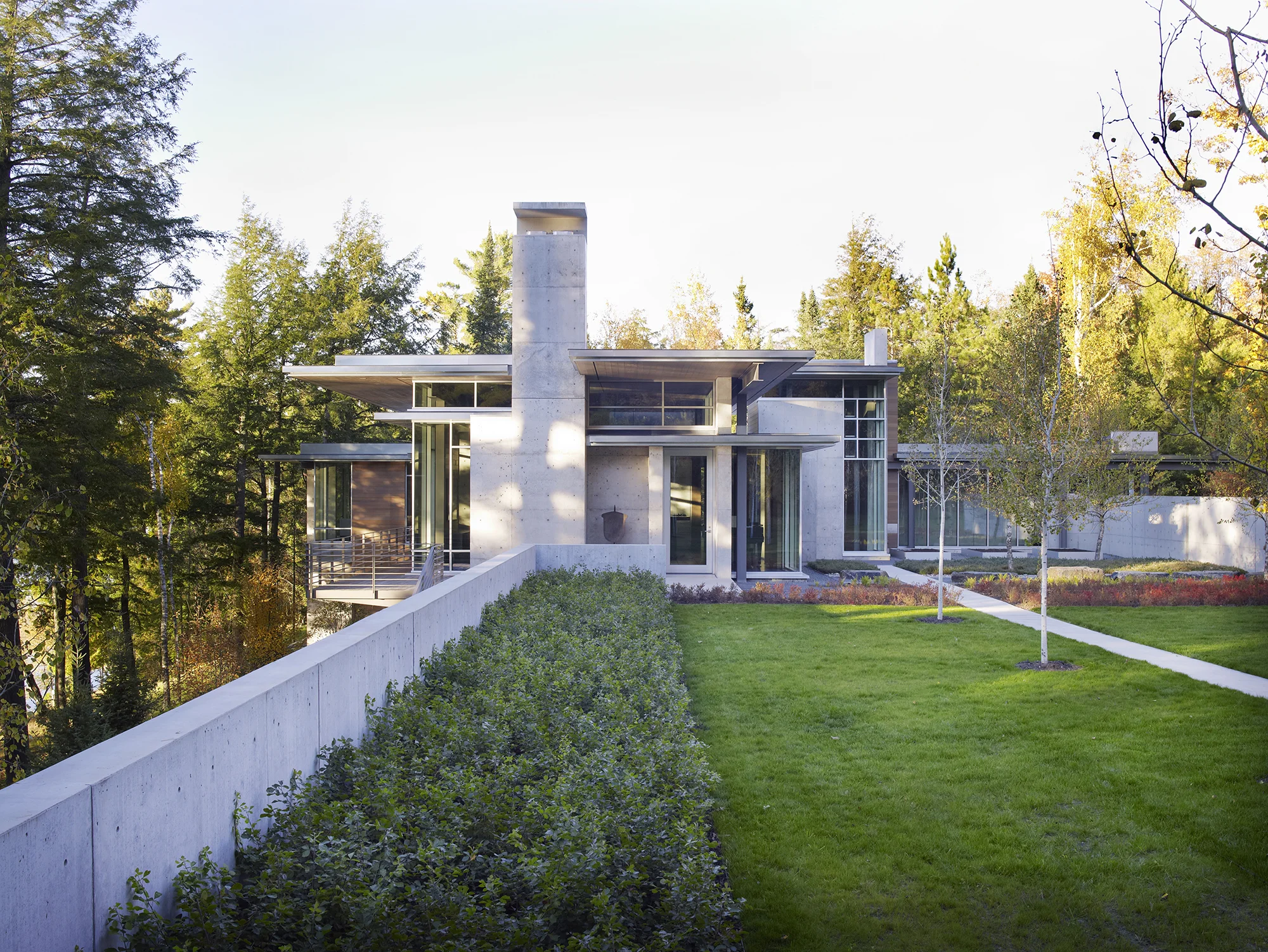 This rural site is set within a larger preserve at the edge of Lake Hagerman in the North Woods of Michigan’s Upper Peninsula. A new residence blurs the boundaries between interior and exterior space, taking advantage of significant views and physical connections to the surrounding forest and water’s edge. The site is organized as a series of woodland gardens that takes cues from the surrounding landscape of blueberry, bearberry, sumac, fern, shad, quaking aspen, birch, and spruce. Site water and drainage feed a passive water feature on the west side, and an active runnel moves water through an entry courtyard of site salvaged bedrock, gravel, and perennials. Durable materials are shared collectively between architecture and landscape, including aluminum, cast in place concrete, and wood. Collaborators Olson Kundig Architects Photography Ngoc Minh Ngo