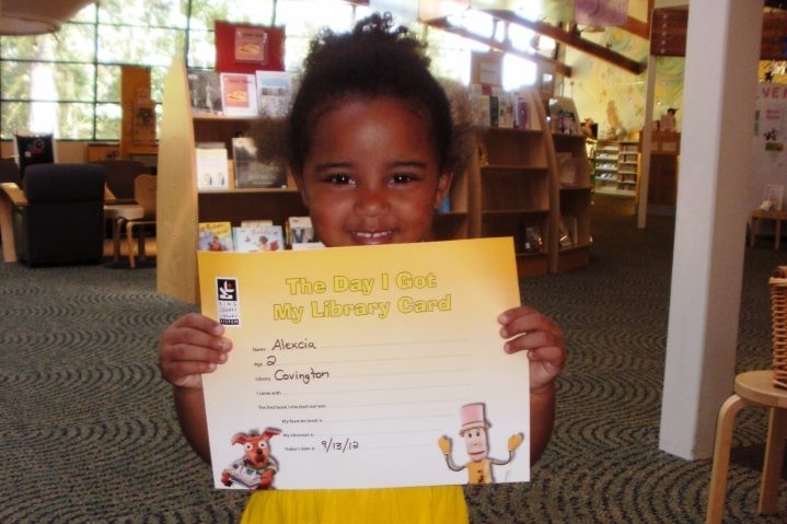 Child holding First Library Card Certificate.jpg