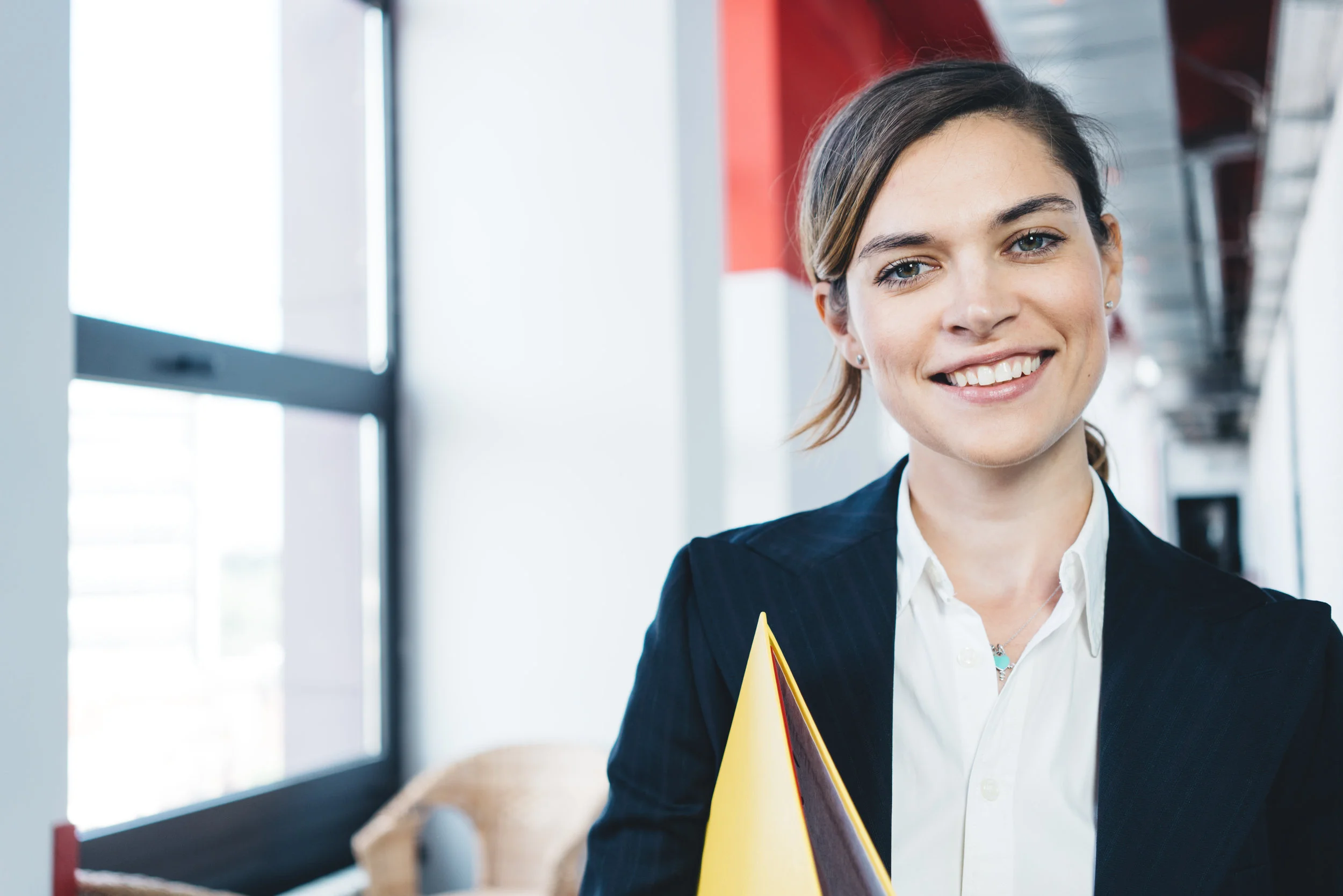 Portrait of smart casual dressed charming business woman with paperwork standing in the office