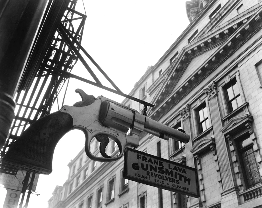 Gun Store sign in City street shaped like gun