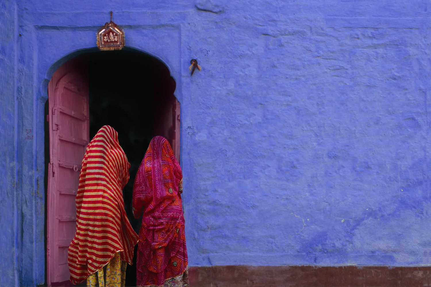 two indian women pink door lavendar wall