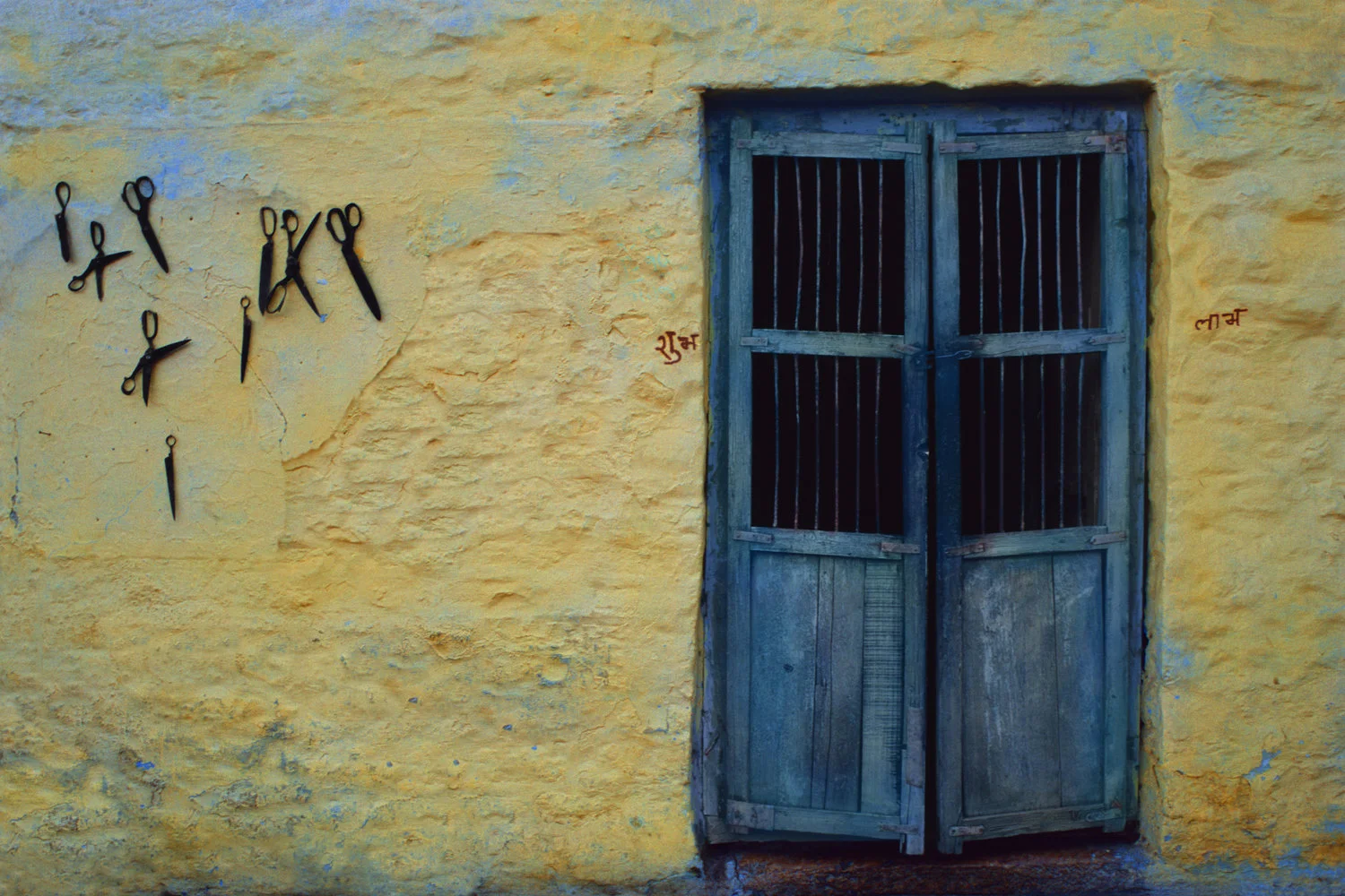 Scissors hanging on wall outside blue doors