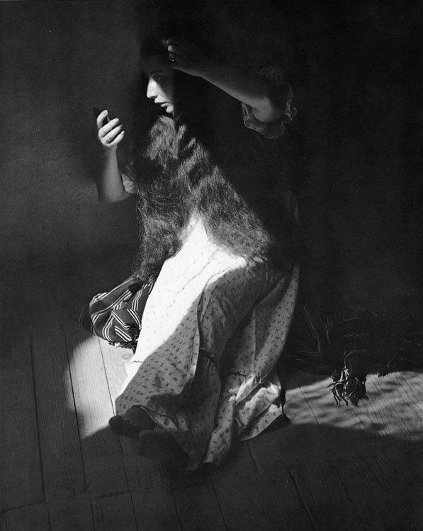 woman nightdress with long hair in light shaft looking into mirror