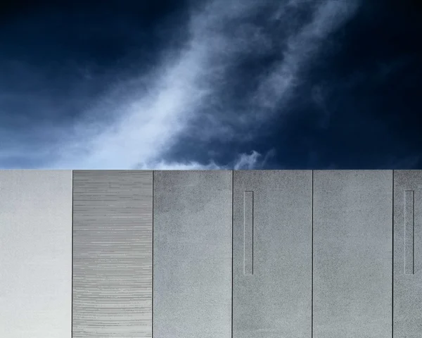 dark cloudy sky intersected by cement slab wall