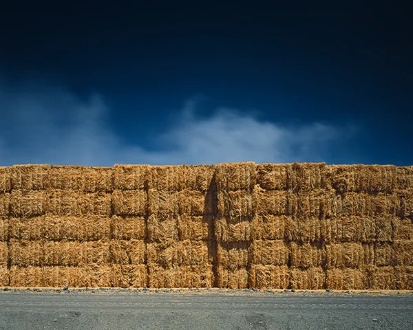 blue sky intesected by wall of hay bails