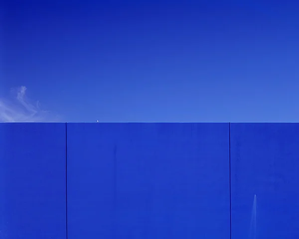 blue sky bisected by cobalt blue wall
