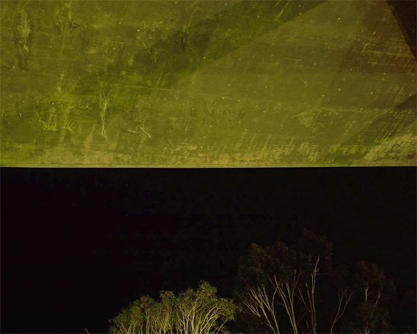 cement cieling bisected by nightsky trees green light