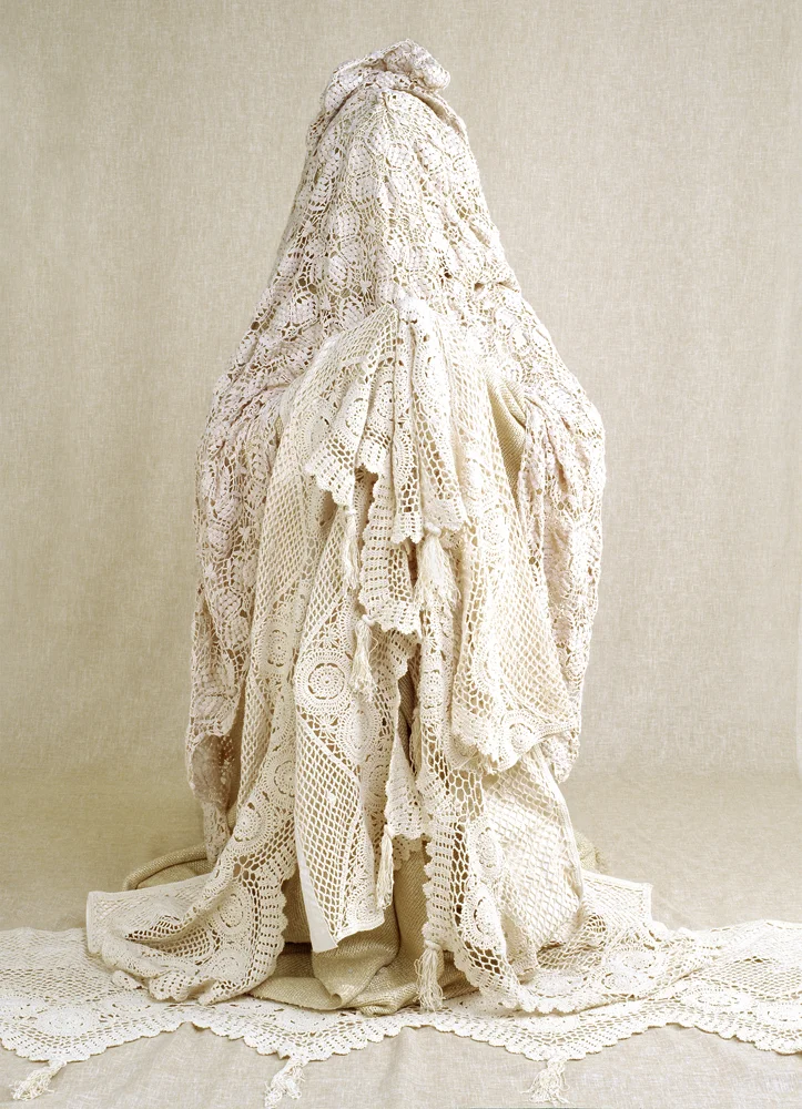 model draped in heaps of crotchet and lace material obscurring face
