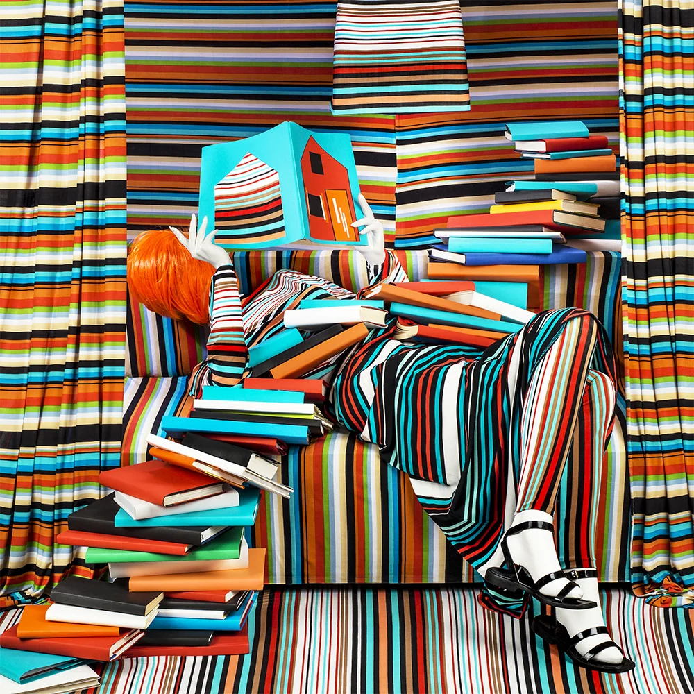 woman reading books on pile of books everything stripe coordinated