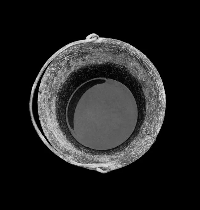 top view of a metal bucket with liquid on black background