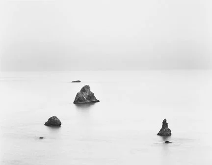 3 rocks in misty water coastline