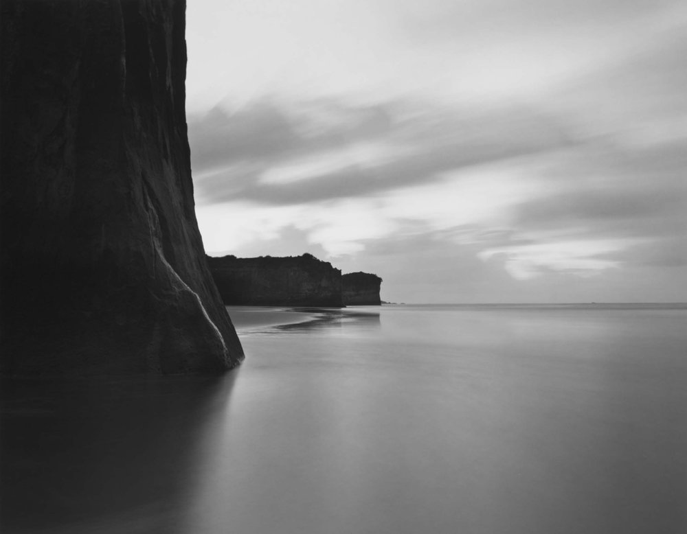 vertical stone meets beach sand