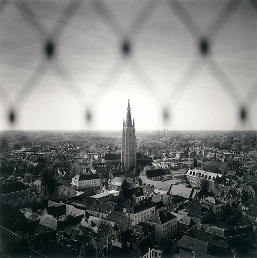 view of steeple and city through fence