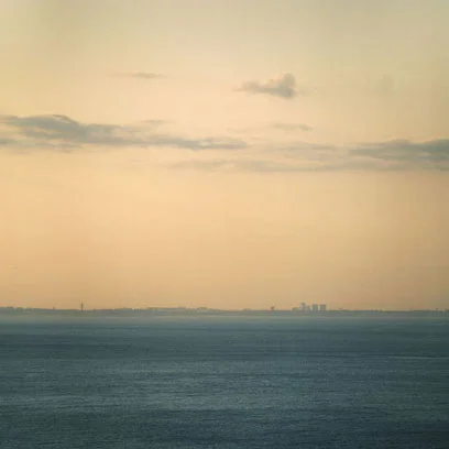 seascape pale sky city horizon grey water