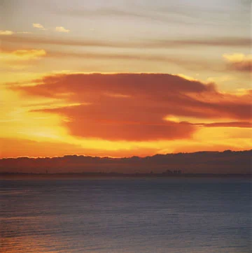 large orange cloud seascape city horizon