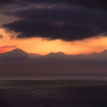 dark clouds orange sliver sky black sea