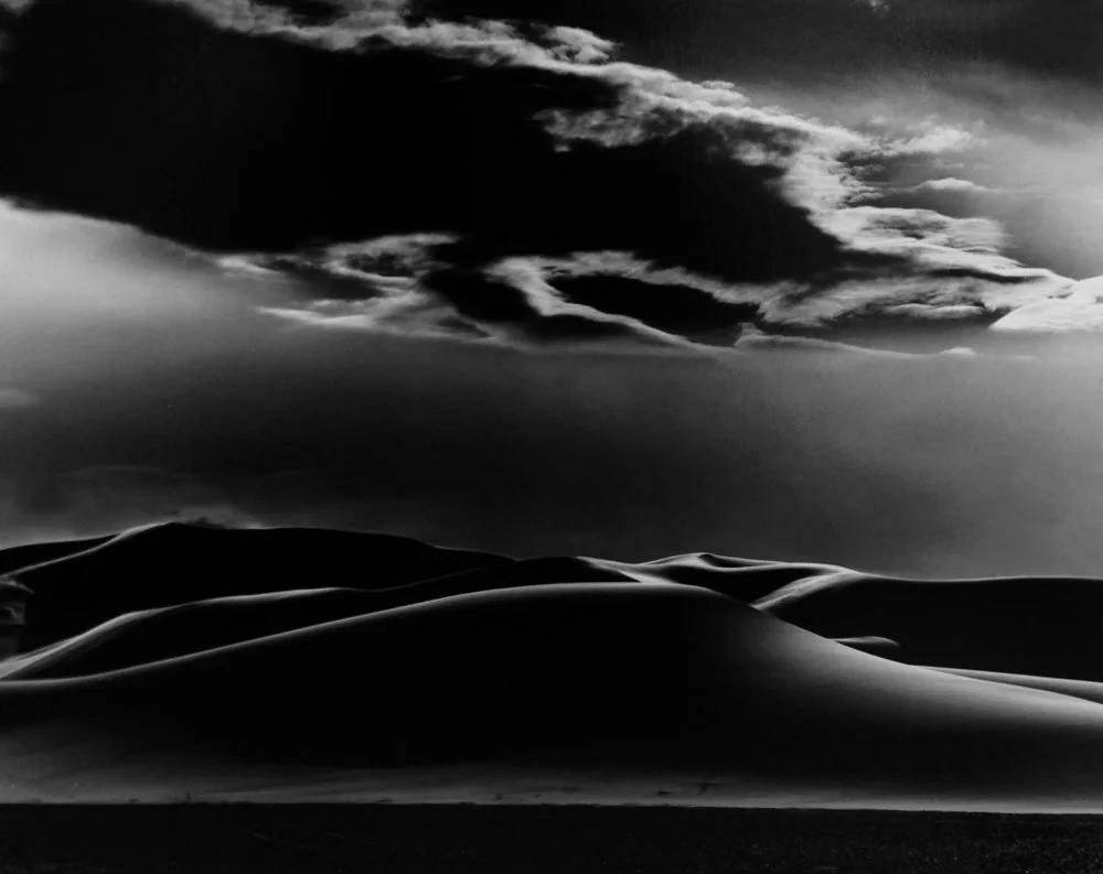 high contrast desert dunes mirror black clouds