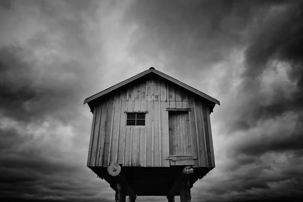 elevated shack against low dark clouds