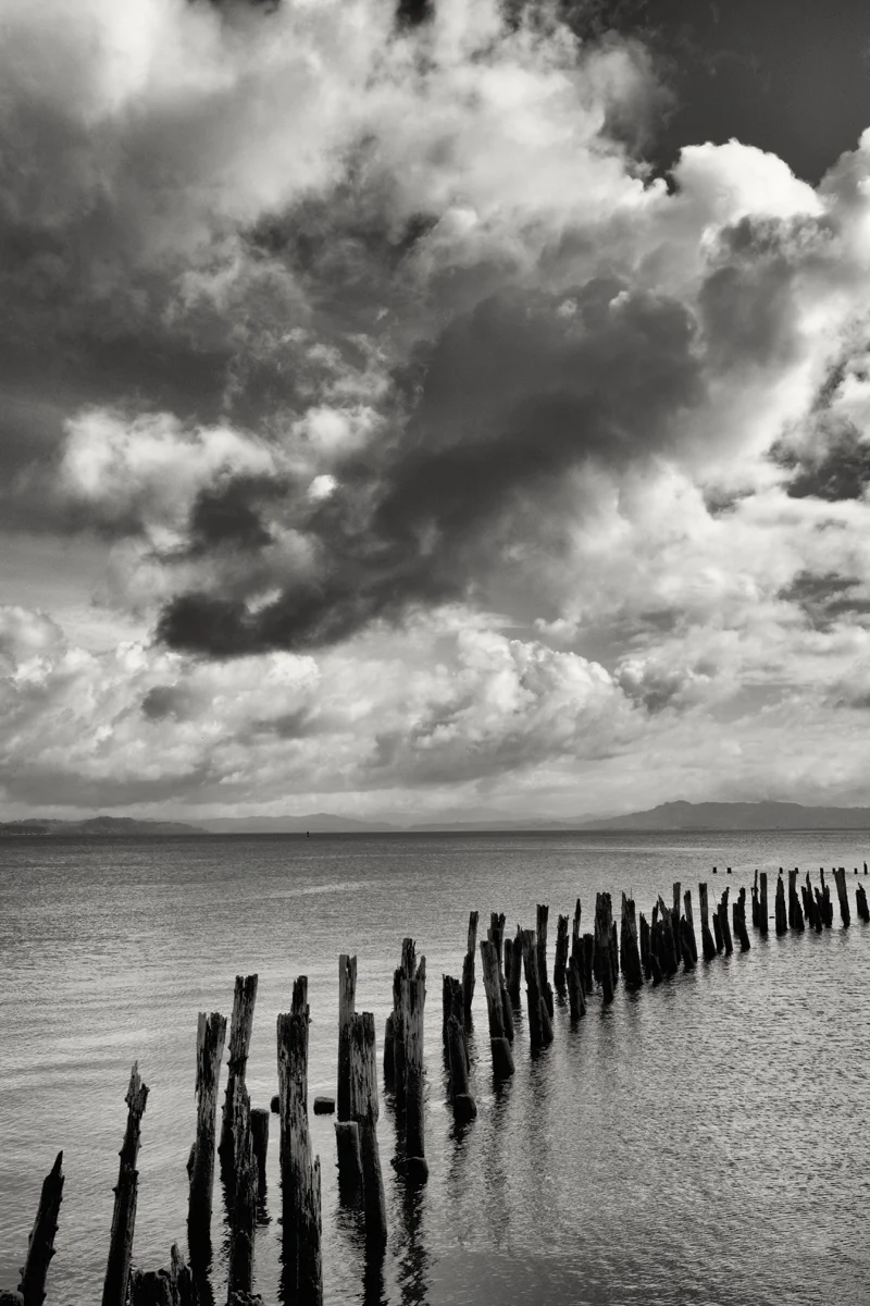 seascape poles rising from water thick clouds
