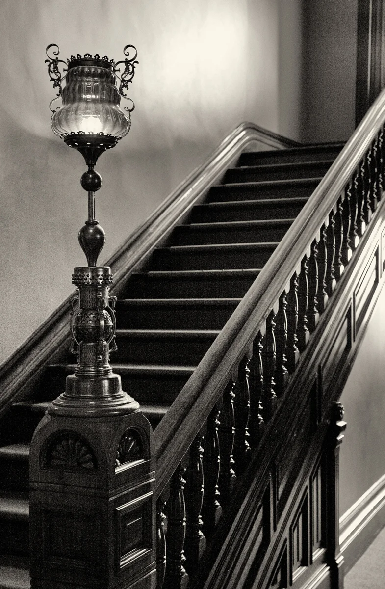 view ascending wooden stairs banister lamp