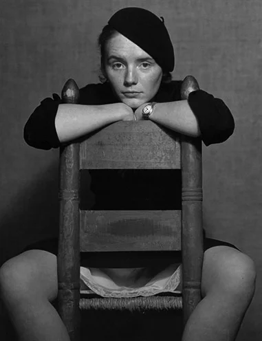 woman stratling wood chair in beret