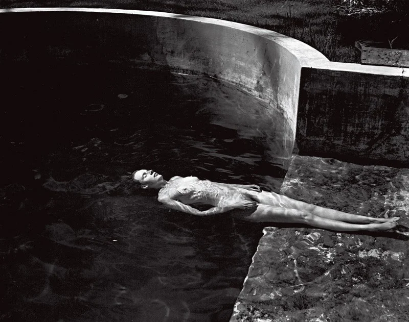 nude woman floating in pool