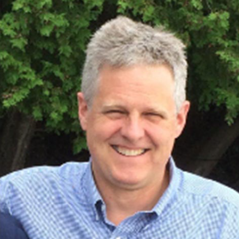 Ben Baldwin standing in front of a tree in a vlue and white checked shirt.