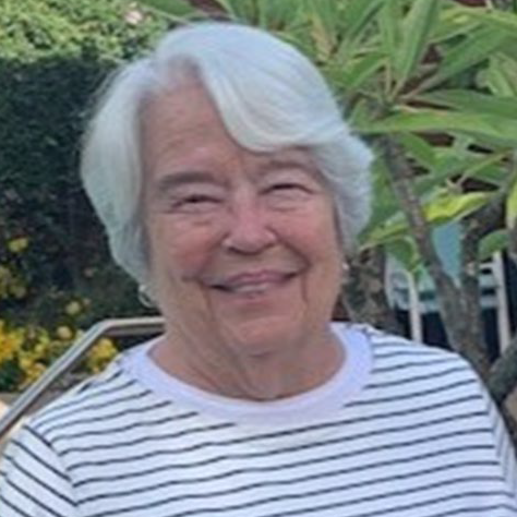 Betsy Carr standing in front of a tree with a white and greey striped shirt.