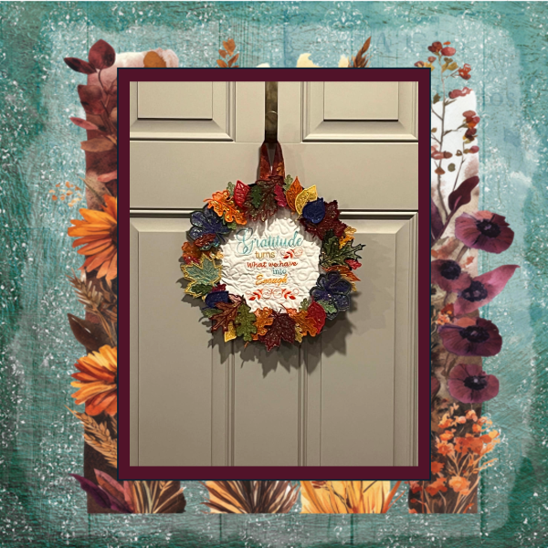 11 colorful Mylar applique autumn leaves stitched in the hoop, arranged as a decorative fall wreath with gratitude saying.
