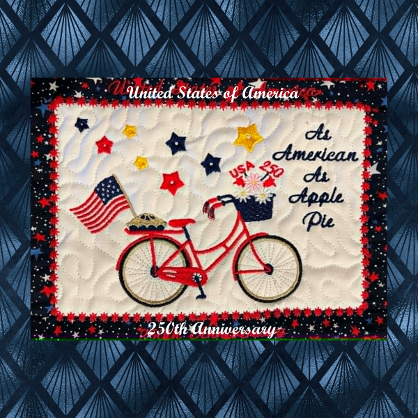 Patriotic USA 250th anniversary in-the-hoop embroidery wall hanging featuring a red bicycle, apple pie, American flag, stars, and festive Americana quilted border.
