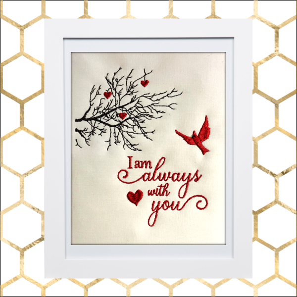 Machine embroidery design for framing, throw pillows, etc., with cardinal bird, tree branches, small hearts, and the phrase “I am always with you” in red script on a neutral fabric background