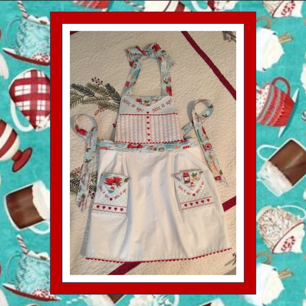 Vintage-style embroidered apron with Mix It Up text, heart accents, rick rack trim, and buttoned flap pockets, created using In the Hoop machine embroidery 2.
