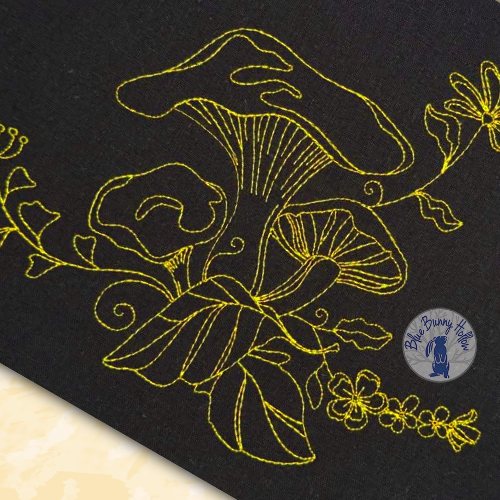 Close-up of Pixie Shroom embroidery showing fine line art details stitched with 60-weight thread.