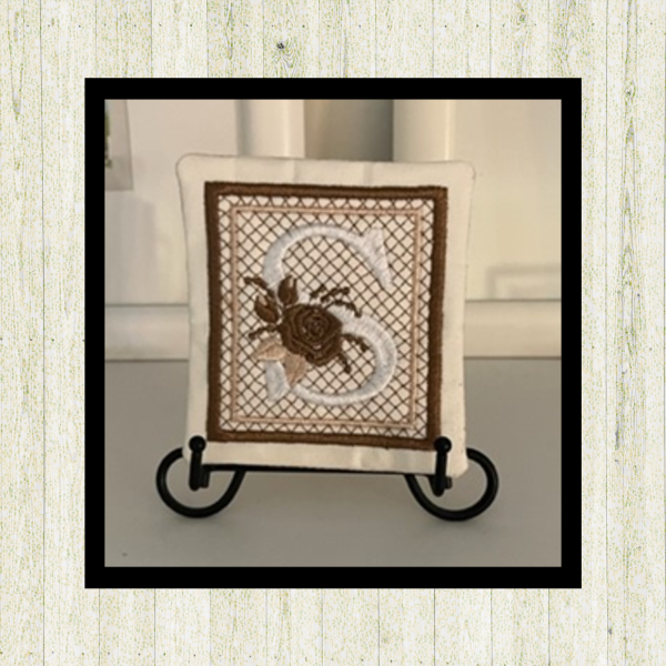 Cream letter "S", rose-monogram mini quilt machine embroidery design, setting on easel, featuring decorative alphabet letters stitched in the hoop for personalized home décor and gift giving. (Copy)