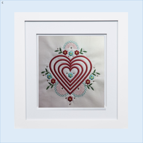 Four stacked red hearts embroidery mug rug design with floral accents framed