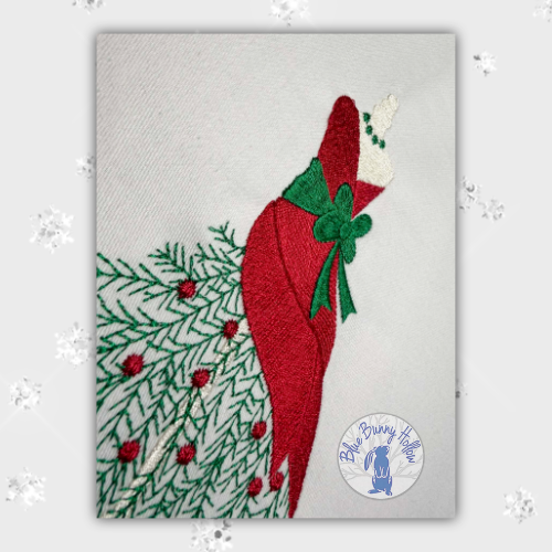 Close-up view of the red holiday dress and green waist bow from the 2025 Christmas Mannequin embroidery design, digitally embroidered. (Copy)