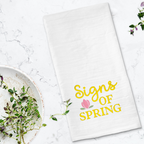 Signs of Spring embroidery design with flower stitched on a towel.