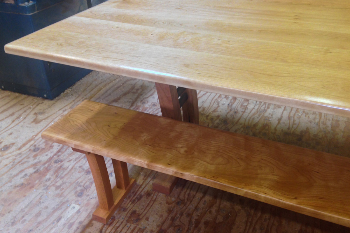 Curly cherry table with arched legs and matching bench.