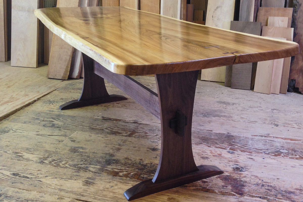 Live edge elm slab table top with a walnut trestle base.