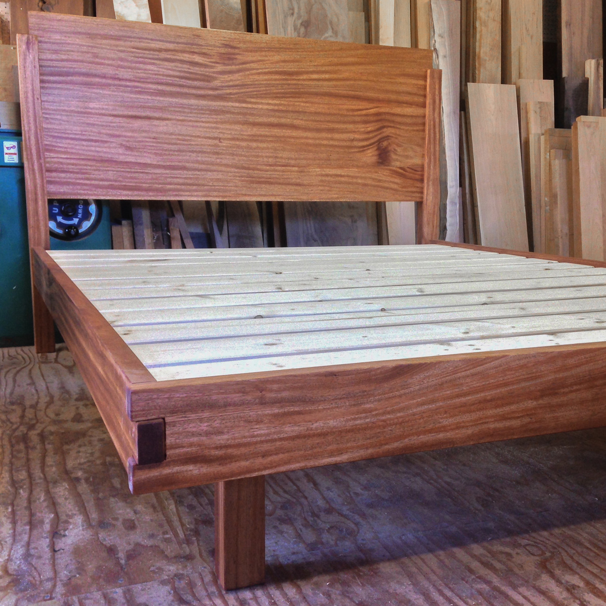 Mahogany platform bed with box joint footboard and recessed legs.