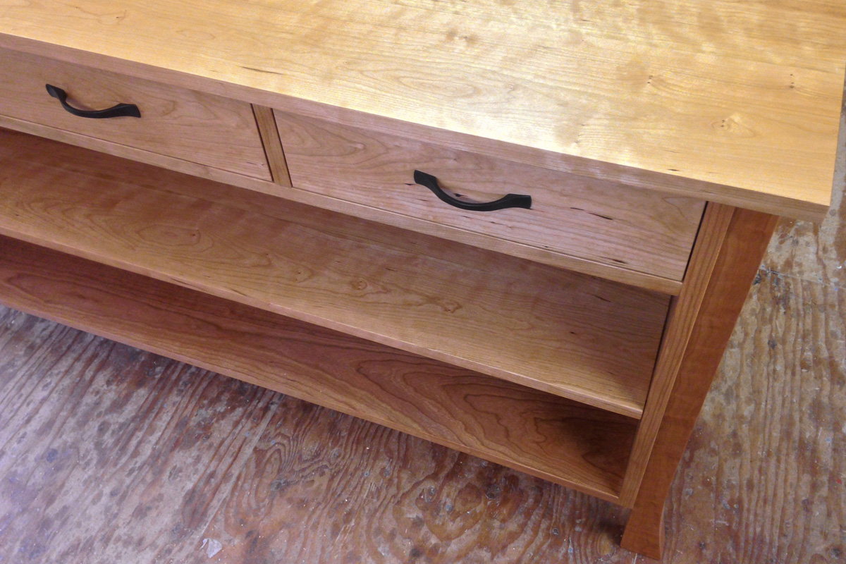 A sideboard with three upper drawers and an adjustable lower shelf in an all cherry design.