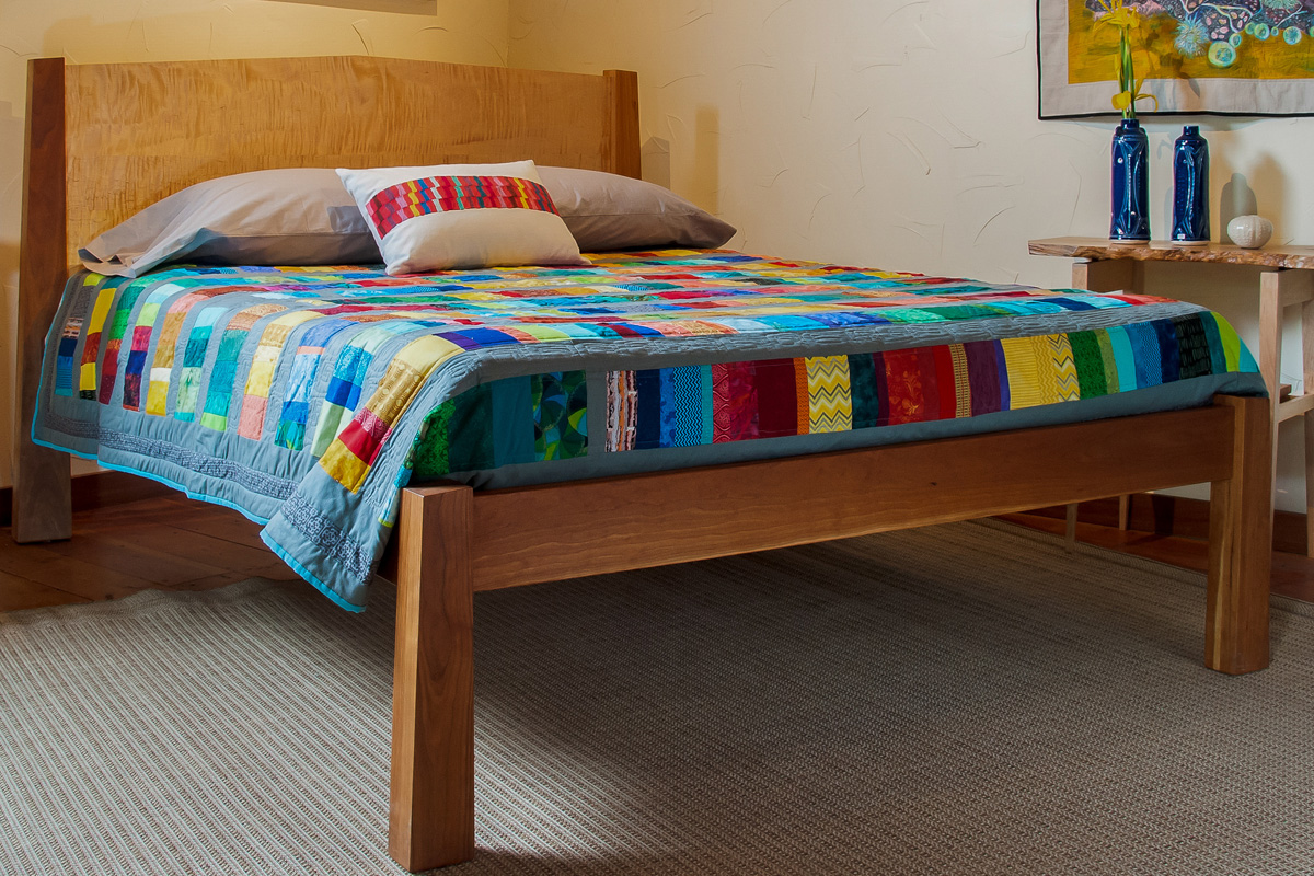 Cherry bed frame with quilted maple headboard panel.