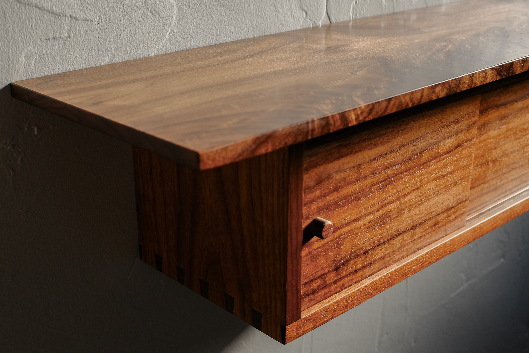 Detail of door and figured walnut grain on shelf.