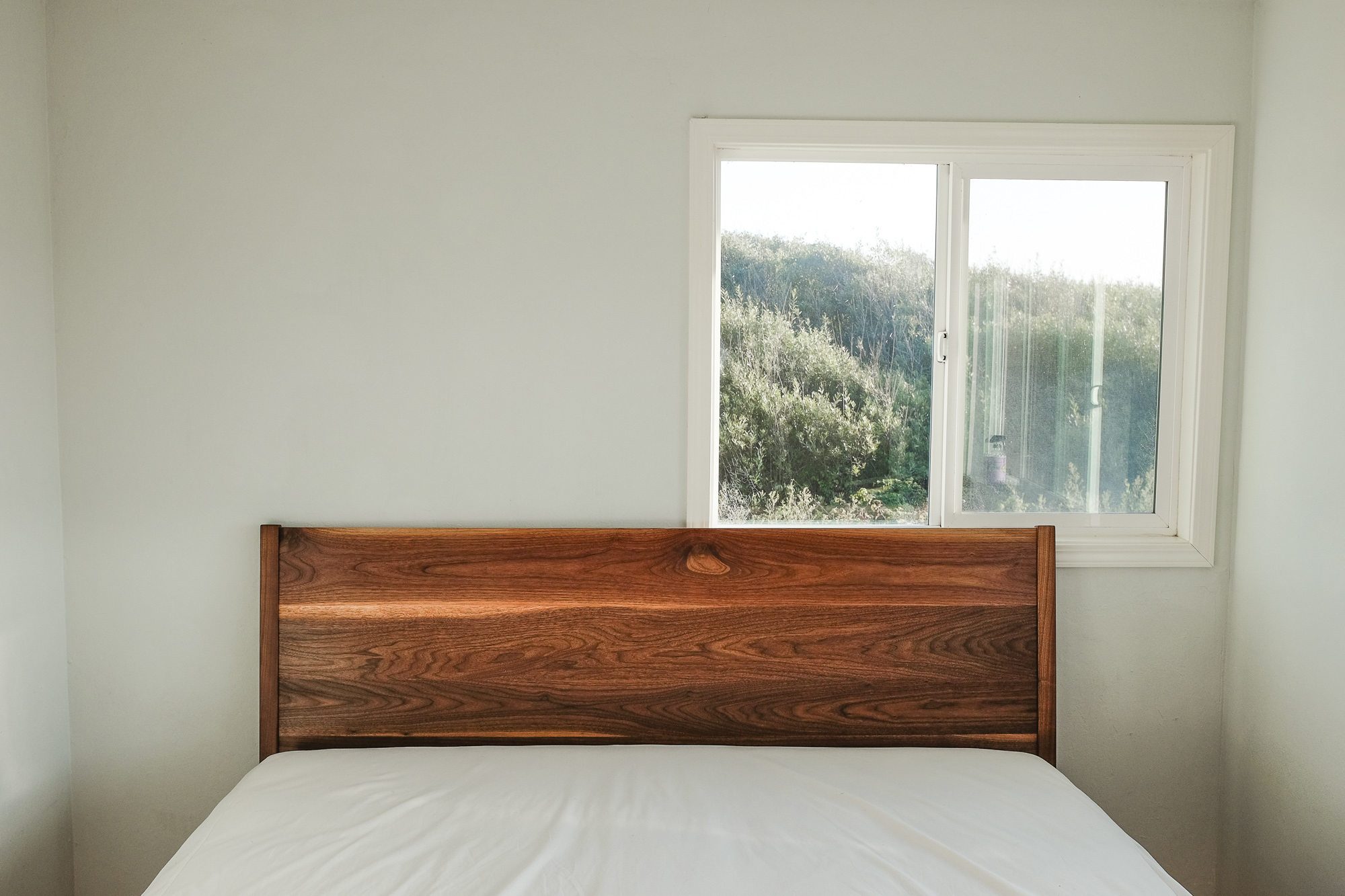 An angled walnut headboard for a platform bed design.