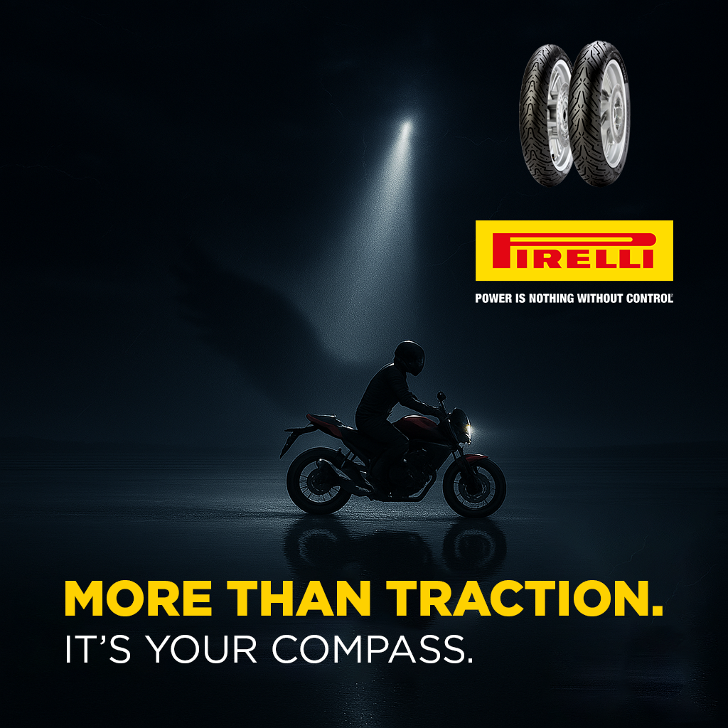 Motorcycle rider wearing a helmet riding at night on a dark road with a spotlight shining on a pair of Pirelli tires and the Pirelli logo. Text reads 'More Than Traction. It's Your Compass.'