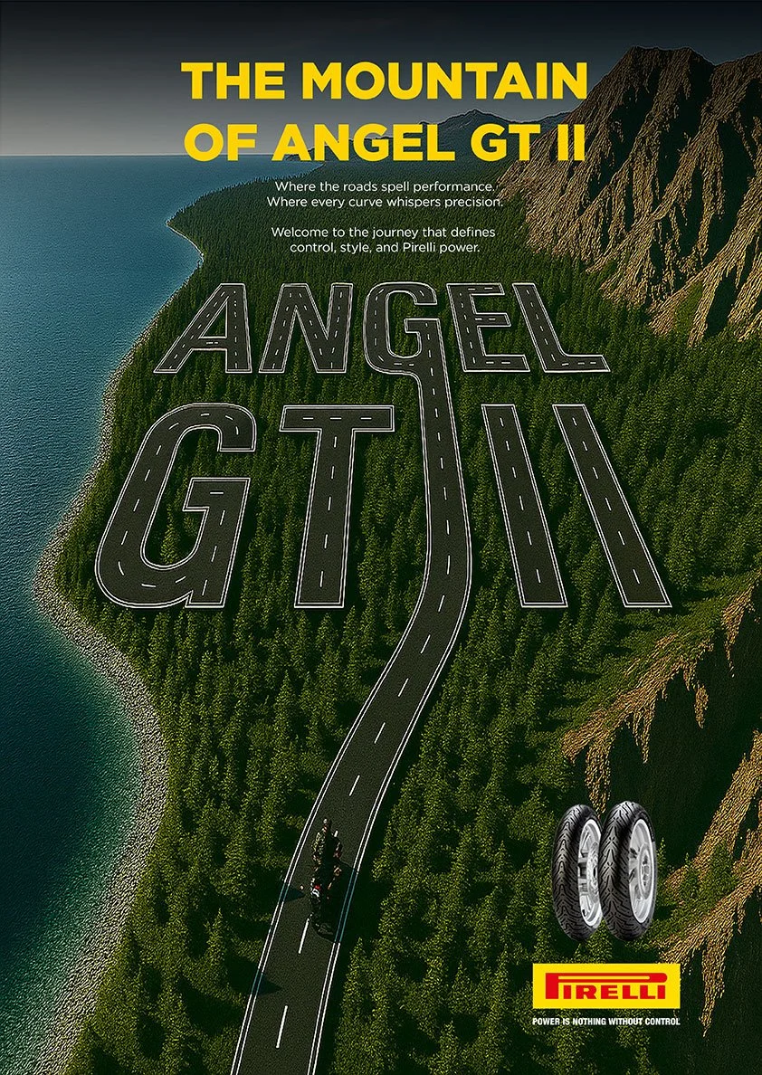 A road winding through a mountainous landscape with trees, with giant letters spelling 'Angel GT II' on the road, and a motorcycle on the road near the bottom. The top has the text 'The Mountain of Angel GT II' in bold yellow. Pirelli logo and slogan are at the bottom right corner.